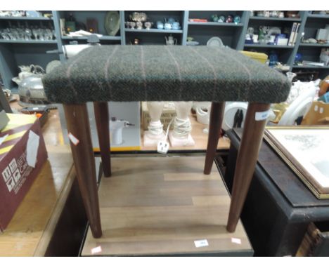 A vintage stool having teak legs and reupholstered tweed seat