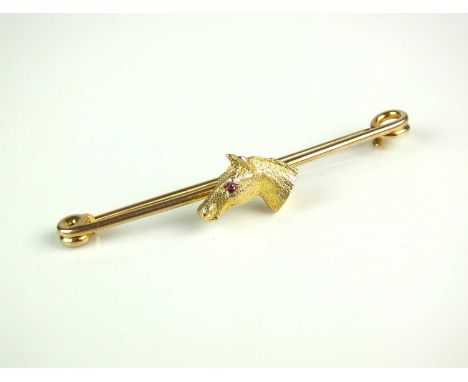 A yellow metal horse head bar brooch/stock pin, the naturalistically modelled head with cabochon ruby set eye, mounted to yel