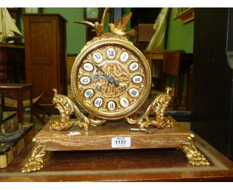 A brass Mantle Clock on a brown marble base having brass bunch of grapes style feet, the face in brass with each Roman numera