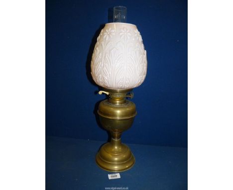 An Oil lamp with brass base having pale pink pressed glass shade with floral motifs (chip to rim), clear chimney, 21" tall.