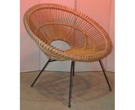 A vintage wicker cone shaped chair, raised on splayed metal legs