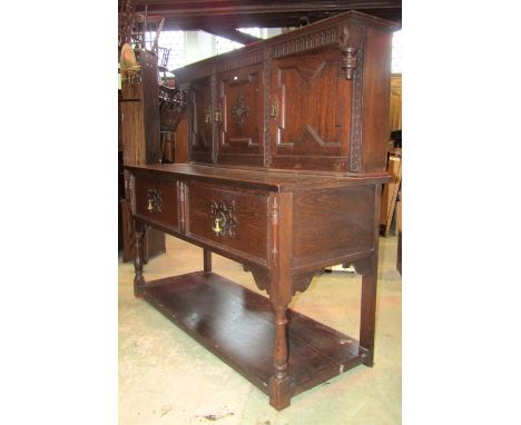 An early 20th century Jacobean revival oak dresser with geometric and further split mouldings , carved foliate and stop flute
