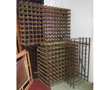 A vintage iron work wine rack, with wave shaped bars, together with two further wine racks of varying size with strap work fr