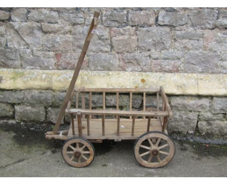 A vintage wooden hand cart, with T shaped handle, spoke wheels and hard rubber tyres