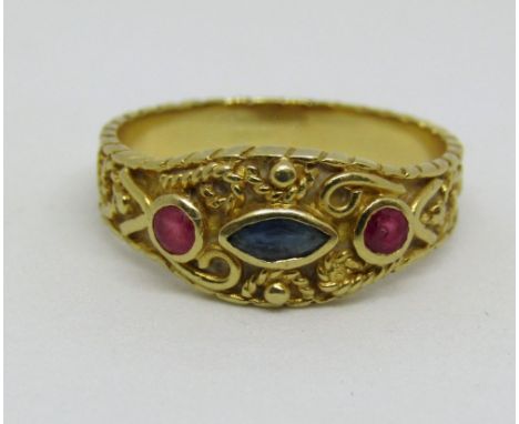 18ct ring set with a marquise cut sapphire flanked by a pair of round cut rubies, the shank with intricate scrolled decoratio