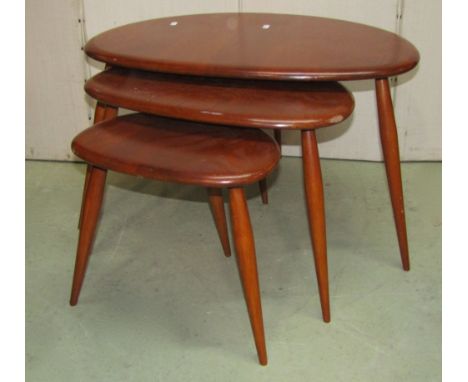 An Ercol medium elm and beechwood nest of three graduated "pebble" occasional tables raised on splayed turned tapered support