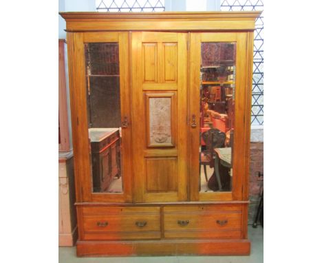 A late Victorian/Edwardian walnut triple wardrobe with moulded cornice over three, three quarter length panelled doors, two w