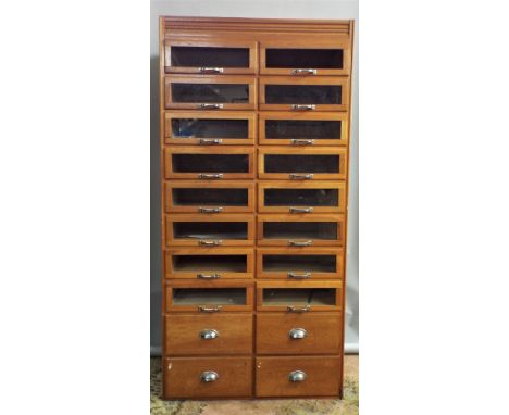 A vintage oak and glass haberdashery cabinet enclosing 16 glass fronted drawers and four timber fronted doors in a side by si