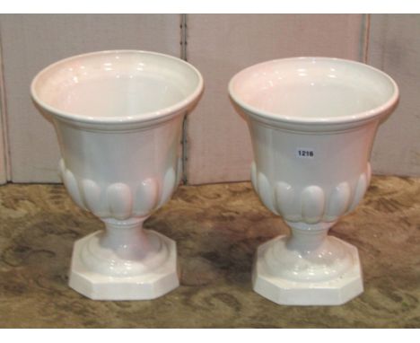 A pair of white glazed ceramic urns, with partially lobed bodies and canted base, 31cm diameter x 40cm high