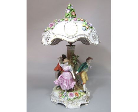 A large continental ceramic two branch table lamp, the base in the form of a tree trunk with four dancing figures, the shade 