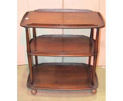 An Ercol dark stained elm and beechwood three tier tea trolley of rectangular form with rounded corners and raised shepherds 