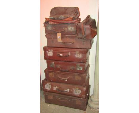 A collection (stack of) seven vintage brown fibre and leather re-enforced suitcases of varying size and design, together with