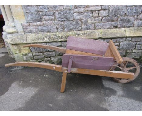 A vintage wooden wheel barrow, with through jointed frame, spoke wheel with iron rim