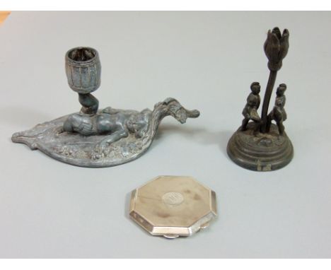 An engine turned silver compact together with a further cast metal, possibly lead candlestick in the form of reclining cherub
