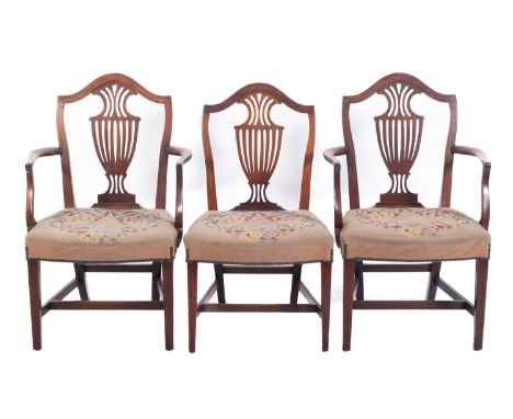 A set of three George III mahogany dining chairs, in the Hepplewhite manner, the backs with arched top rails and pierced cent