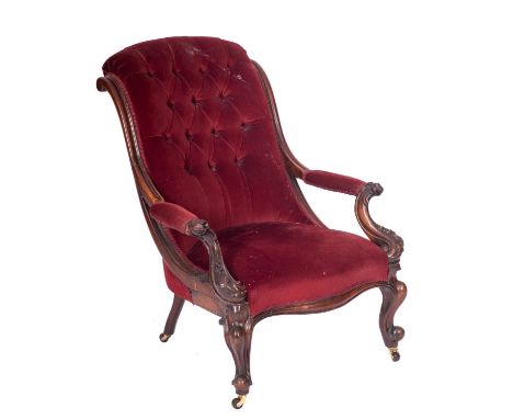 A Victorian carved mahogany open armchair, with upholstered button down curved back, padded arm supports with foliate scroll 