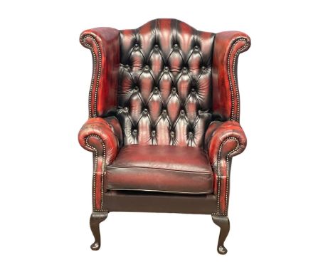 A deep button ox-blood leather wingback armchair on Queen Anne legs. 