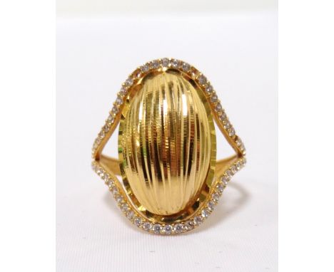 TWENTY-ONE CARAT GOLD RINGthe central textured oval panel with clear stones above and below leading to the split shoulders, r