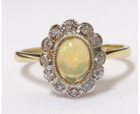 OPAL AND DIAMOND CLUSTER RINGthe central oval cabochon opal in twelve diamond surround, on eighteen carat gold shank, ring si