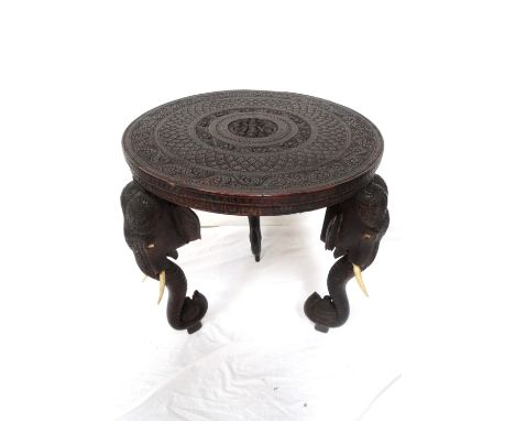 CARVED INDIAN TEAK OCCASIONAL TABLEearly 20th century, with a circular carved top centred with a deity and two birds of parad