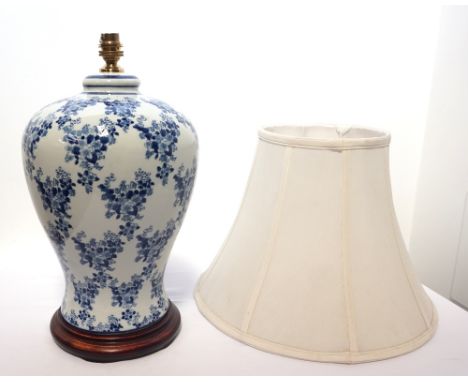 CHINESE BLUE AND WHITE CERAMIC LAMP BASEwith blossom decoration, raised on a circular wooden base, 37.5cm high (excluding fit