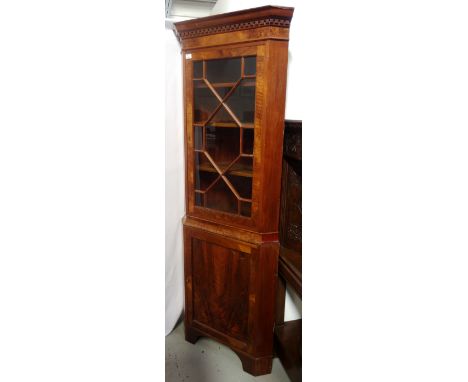 EDWARDIAN WALNUT CORNER CABINETwith moulded cornice, above a glazed astragal door with shelf interior, over a cupboard base w