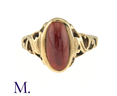 A Garnet Ring in 9k yellow gold, the central oval cabochon garnet accented by scrolling shoulders. Full British Hallmarks, Ma