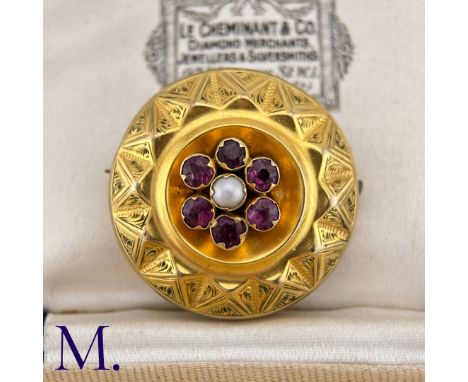 An Antique Garnet And Pearl Mourning Brooch in yellow gold, designed as a pearl within a round cut garnet border with engrave