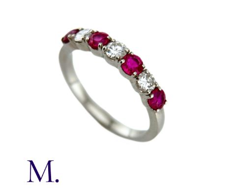 A Ruby And Diamond Seven Stone Ring in platinum, set with an alternating row of four round cut rubies and three round brillia