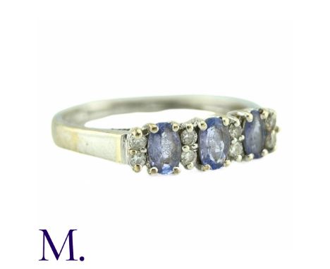 A Tanzanite And Diamond Ring, in 9k white gold, the three oval cut tanzanites punctuated by pairs of round cut diamonds. Size