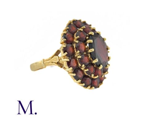 NO RESERVE - A Garnet Cluster Ring in 18k yellow gold, designed as a central oval cut garnet surrounded by two rows of round 