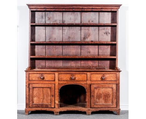 A George III oak dresser, with a matched three shelf delft rack under an ogee moulded cornice, the base with three drawers, a