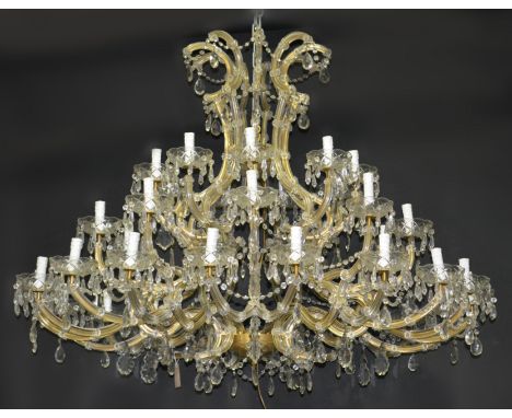 An impressive thirty-six light cut glass chandelier,  scrolled branches issuing from nine S-scrolls, each with lobed and dish