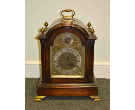 An oak bracket clock, arched top with gilt metal urn finials, arched brass face with silvered chapter ring and slow-fast dial