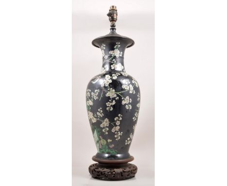 A Chinese famille noire baluster shape vase, serving as a lamp base, decorated with blossom and birds, carved wood stand, met