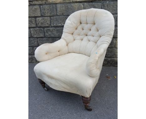 A Victorian button back upholstered armchair on turned walnut legs and brass castors. 