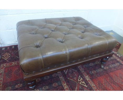 A large button back leather upholstered rectangular stool raised upon castors.