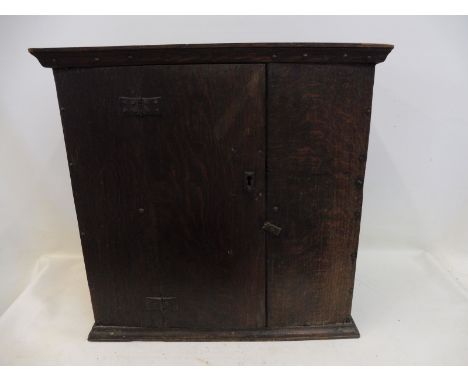 A late 17th/early 18th Century primitive boarded oak mural food cupboard with single door, fitted with a shelf. 