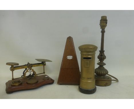A mahogany and brass set of scales, a metronome, a brass money box in the form of a post box and a brass table lamp. 