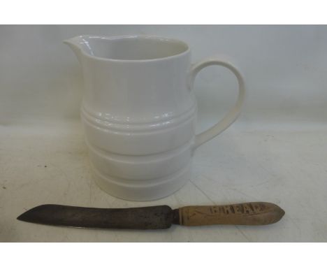 A white ceramic water jug with banded decoration together with a wooden handled bread knife.