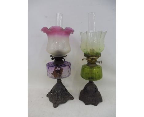 An Edwardian oil lamp with an amethyst tinted reservoir and a pink tinted etched and fluted shade; also one other with a gree