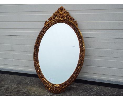 An ornately framed, bevel edge wall mirror, approximately 95 cm x 56 cm.