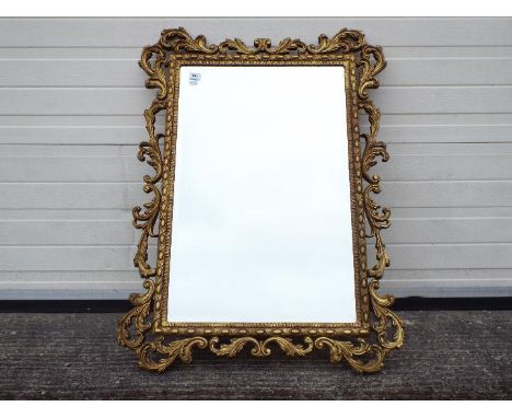 An ornately framed, bevel edge wall mirror, approximately 100 cm x 75 cm.