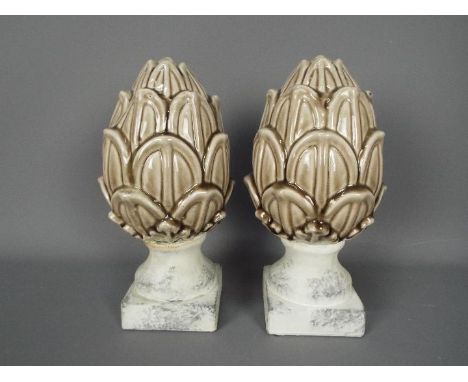 A pair of ceramic artichokes raised on unglazed, marble effect plinths, approximately 28 cm (h). [2]