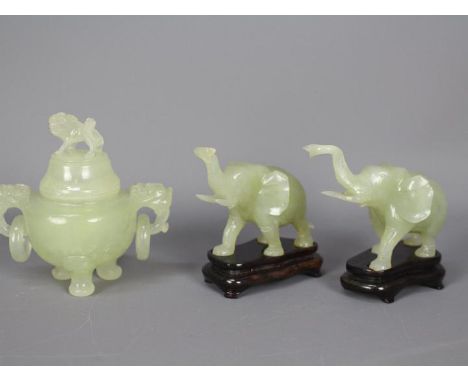 A pair of Chinese, celadon green, bowenite carvings of elephants with raised trunks, approximately 10 cm (h) including wooden