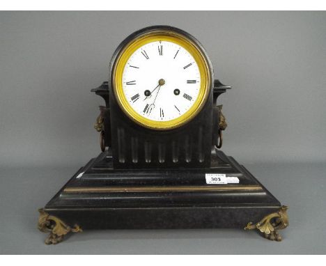 A late 19th century French black slate mantel clock of fluted drum head form, with applied brass trim decoration, supported o