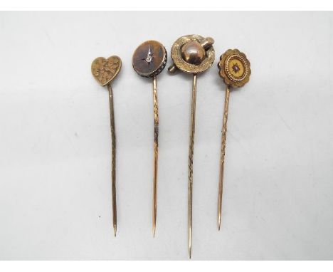 Four yellow metal stick pins, two of which are stone set, each contained in a case.