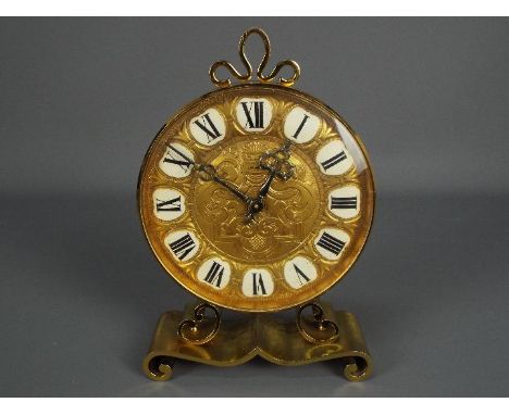A vintage brass mantel clock by Imhof, raised on scrolled supports, approximately 24 cm (h).