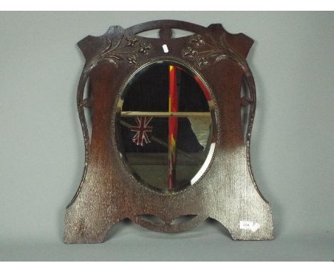 An Art Nouveau style wall mirror with oval, bevel edge plate, approximately 65 cm x 55 cm.