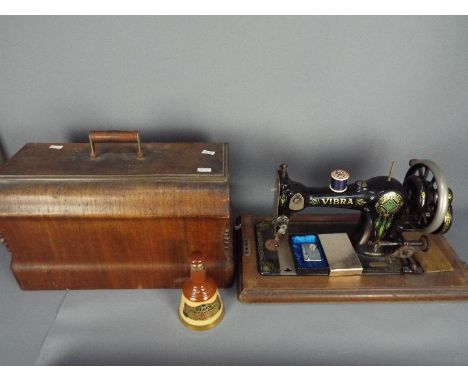 A wood cased Vibra sewing machine, a small Bells whisky decanter and contents, 18.75 cl 40% ABV and a vintage lighter with in